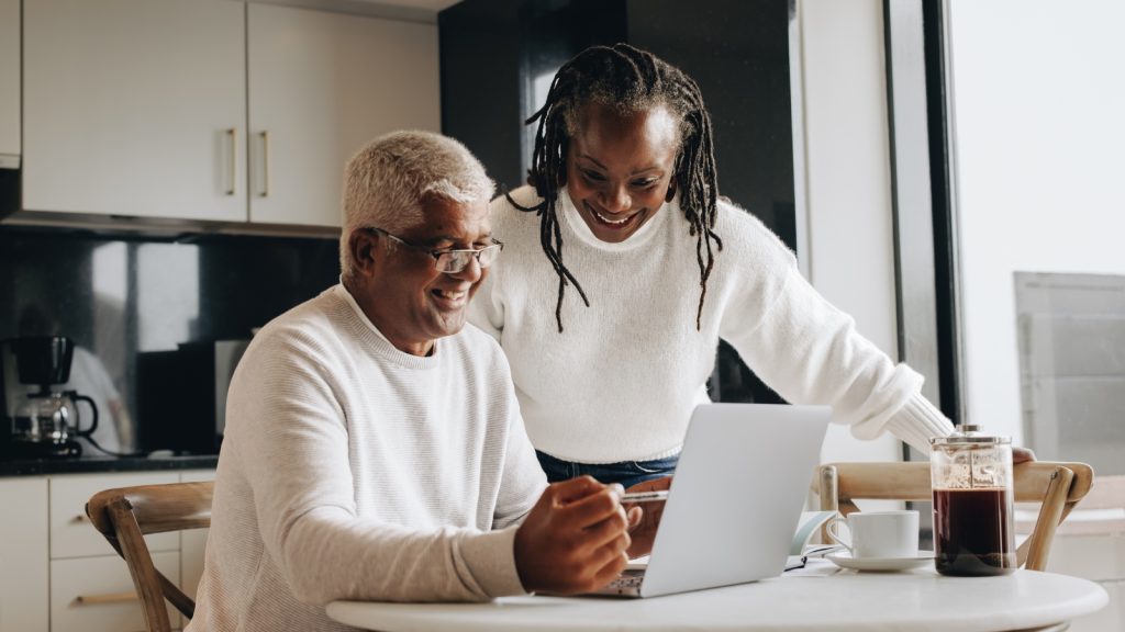 two people at the kitchen table looking at a computer